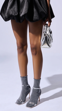 Person wearing black skirt, Shadow Stars gray glittery socks, and silver high-heeled shoes.